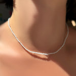 An AMANDA PEARL White Zircon slim gemstone necklace on a model's neck.