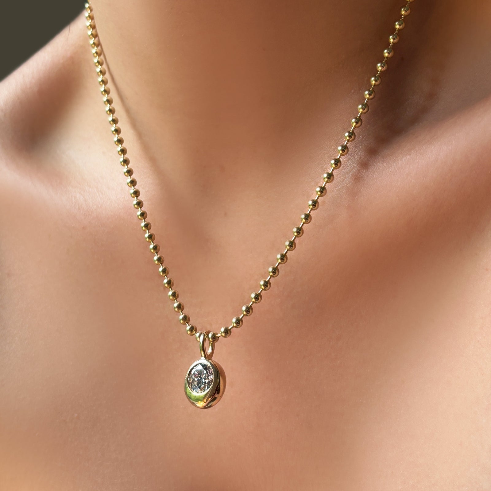 3mm bead chain necklace in yellow gold on the body with a molten solitaire charm with a round diamond.