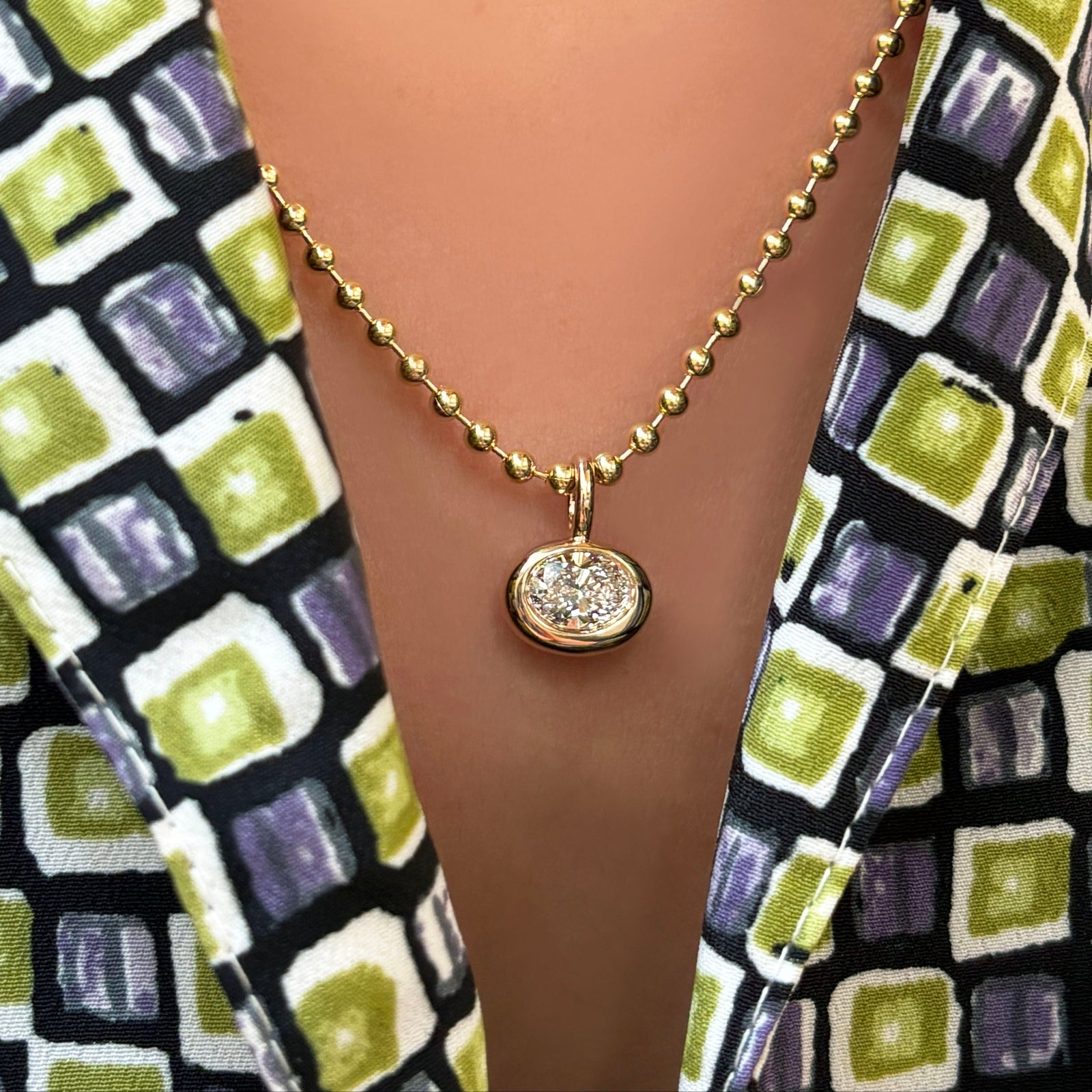 3mm bead chain with small oval molten solitaire charm on a model's neck.