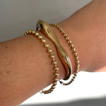 3mm bead chain layered with a gold molten cuff and tibet chain bracelet on a model's wrist.