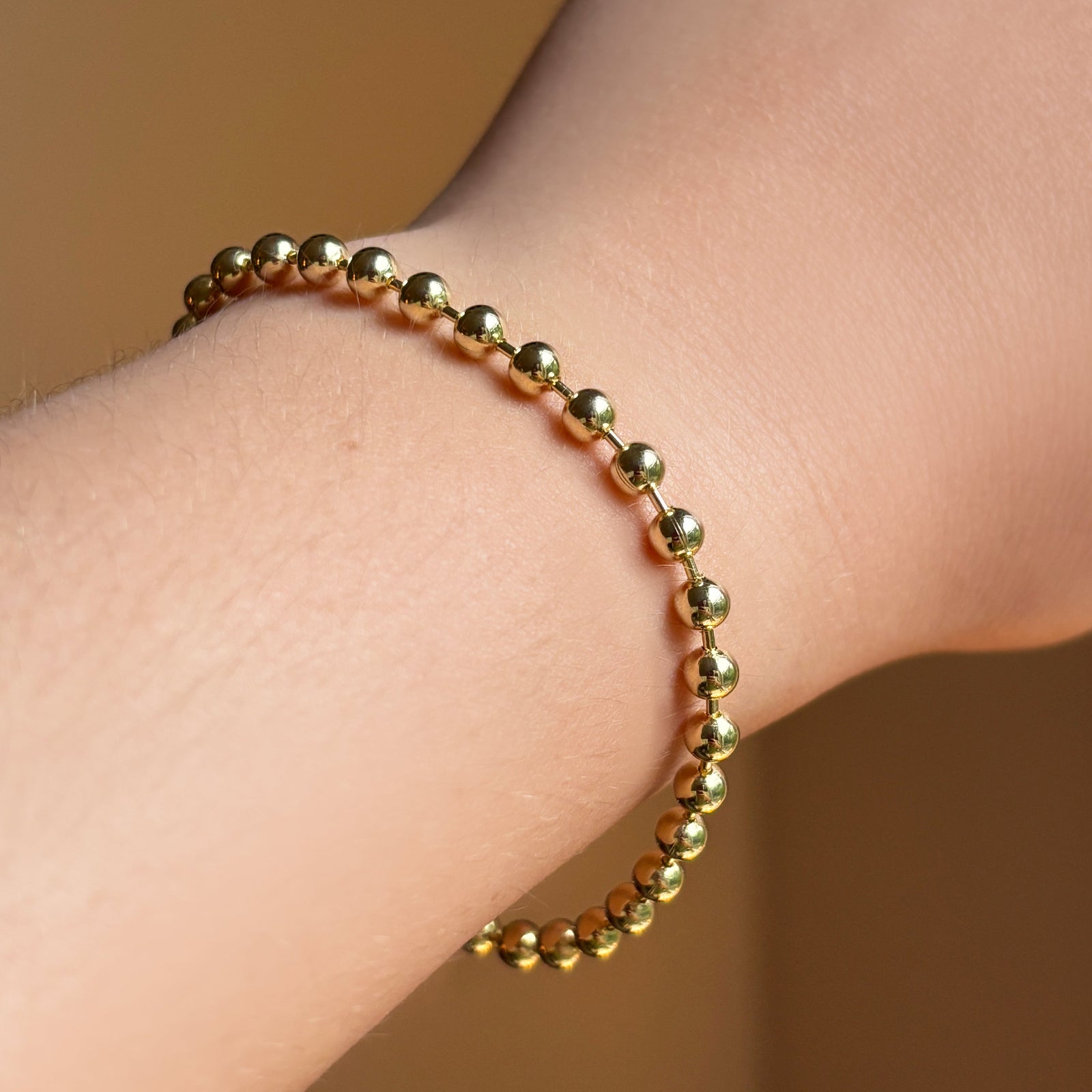 4mm bead chain in yellow gold on the wrist.