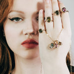 Colorful gemstone rings and charms in organic gold settings.