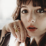 14k recycled gold skull ring on a hand stacked with two molten knot rings