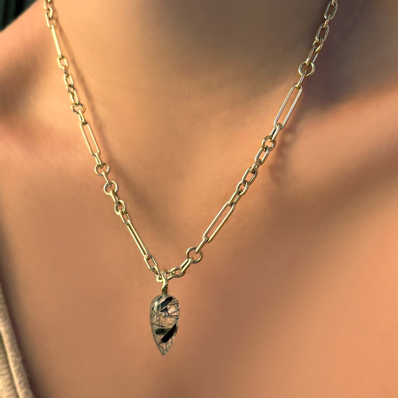 6mm irregular cable chain in yellow gold with a rutilated quartz gemstone drop charm on a model's neck.