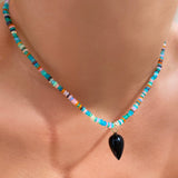Black agate acorn drop charm. Styled on a neck hanging from a beaded necklace