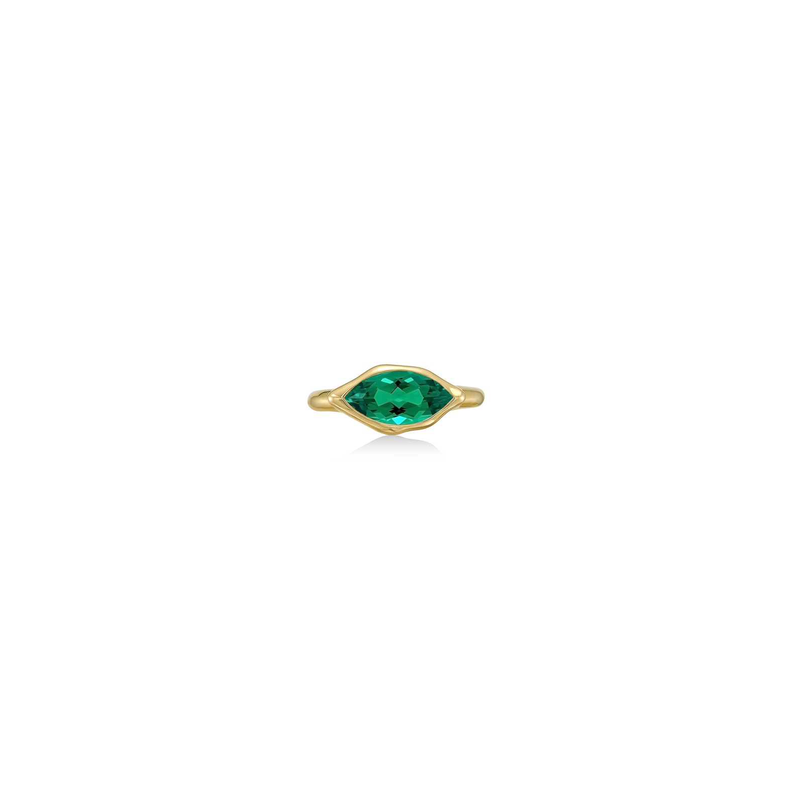 A 14K yellow gold marquise ring, with a bezel set faceted emerald gemstone, sits on a white background with drop shadow.