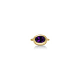 A 14K yellow gold oval ring, with a bezel set faceted amethyst gemstone, sits on a white background with drop shadow.