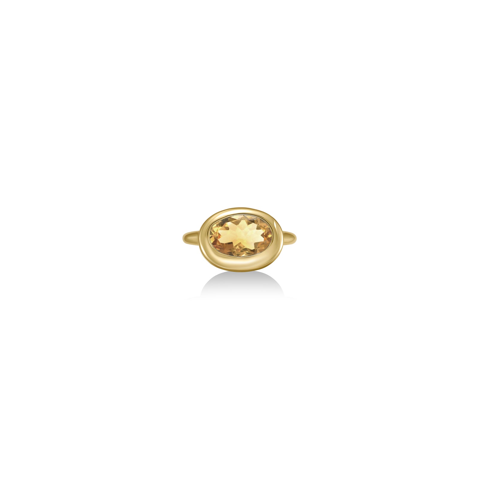 A 14K yellow gold oval ring, with a bezel set faceted citrine gemstone, sits on a white background with drop shadow.