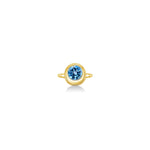 A 14K yellow gold round ring, with a bezel set faceted blue topaz gemstone, sits on a white background with drop shadow.