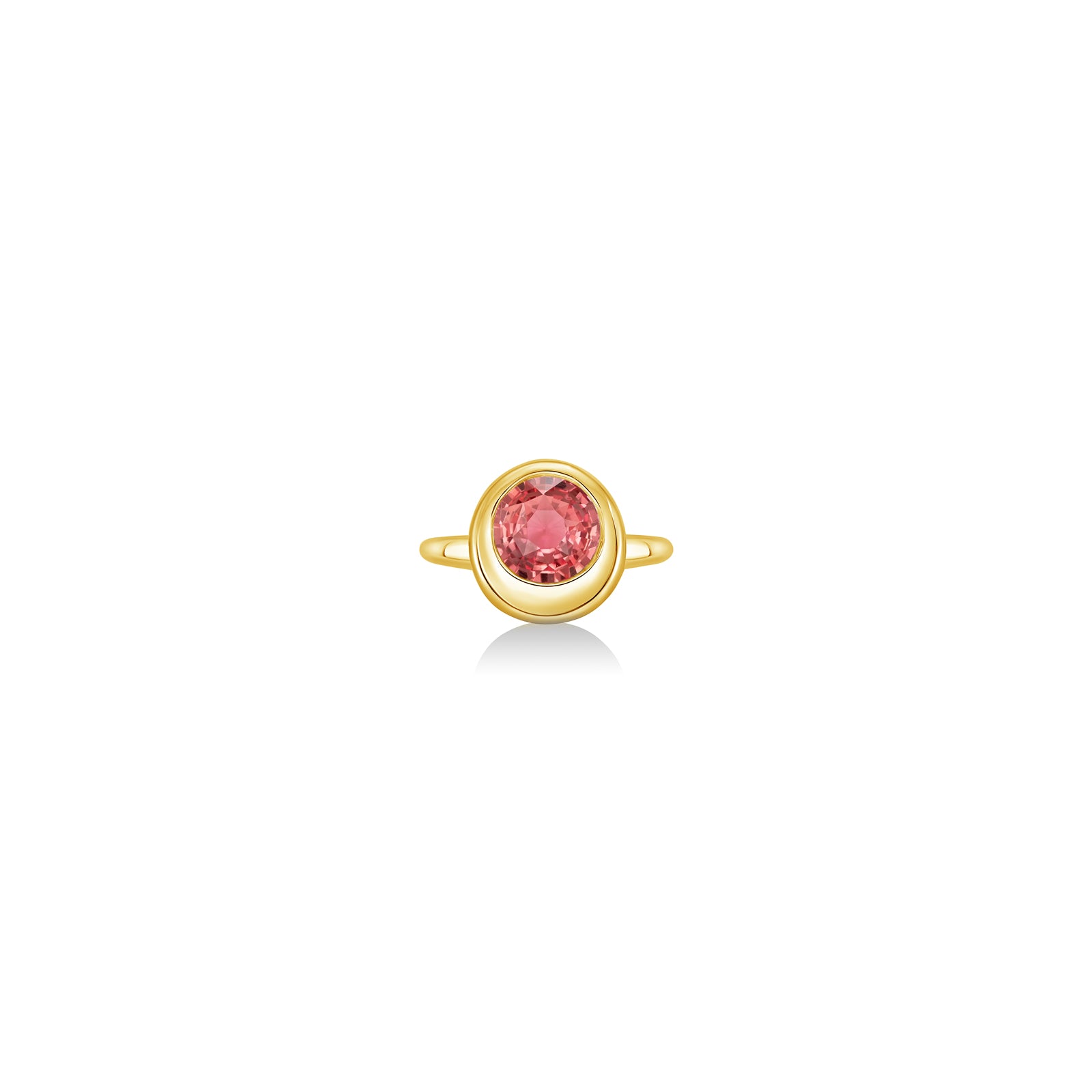 A 14K yellow gold round ring, with a bezel set faceted sapphire gemstone, sits on a white background with drop shadow.