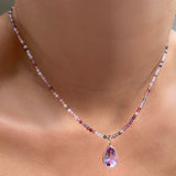 Shimmering slim gemstone beaded necklace made of 2mm faceted stones in tourmaline on a gold linking lobster clasp. Styled on a neck layered with pear solitaire charm.