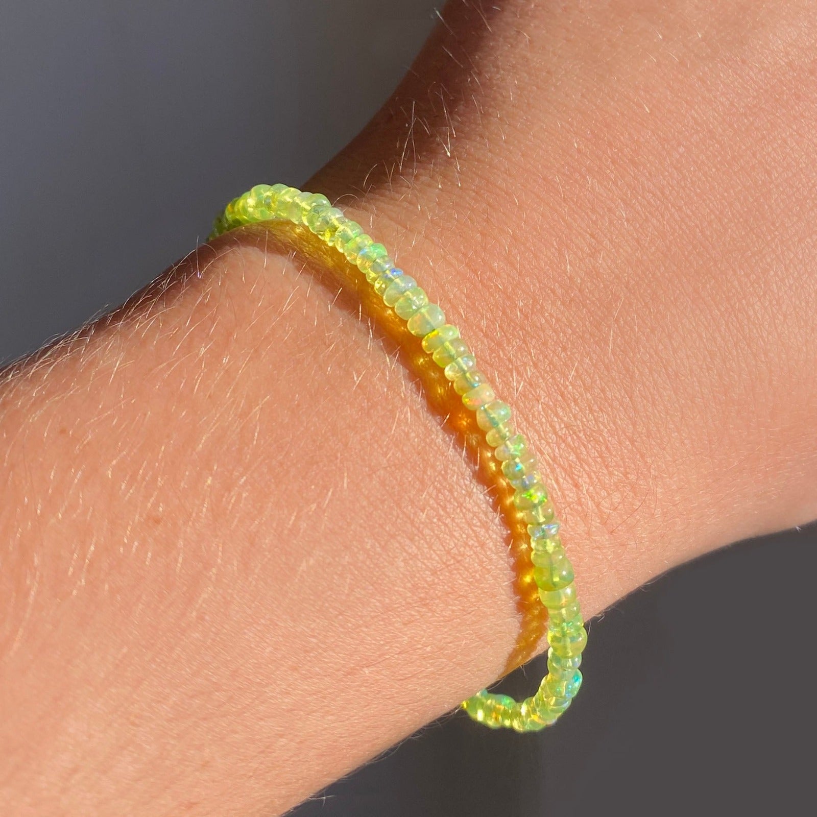 Shimmering Spring Green opal beaded bracelet made of smooth opals in shades of light yellow on a gold linking lobster clasp styled on a wrist