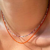 Two shimmering slim gemstone beaded necklace made of 2mm faceted stones layered together in carnelian and tourmaline on a gold linking lobster clasp on a neck