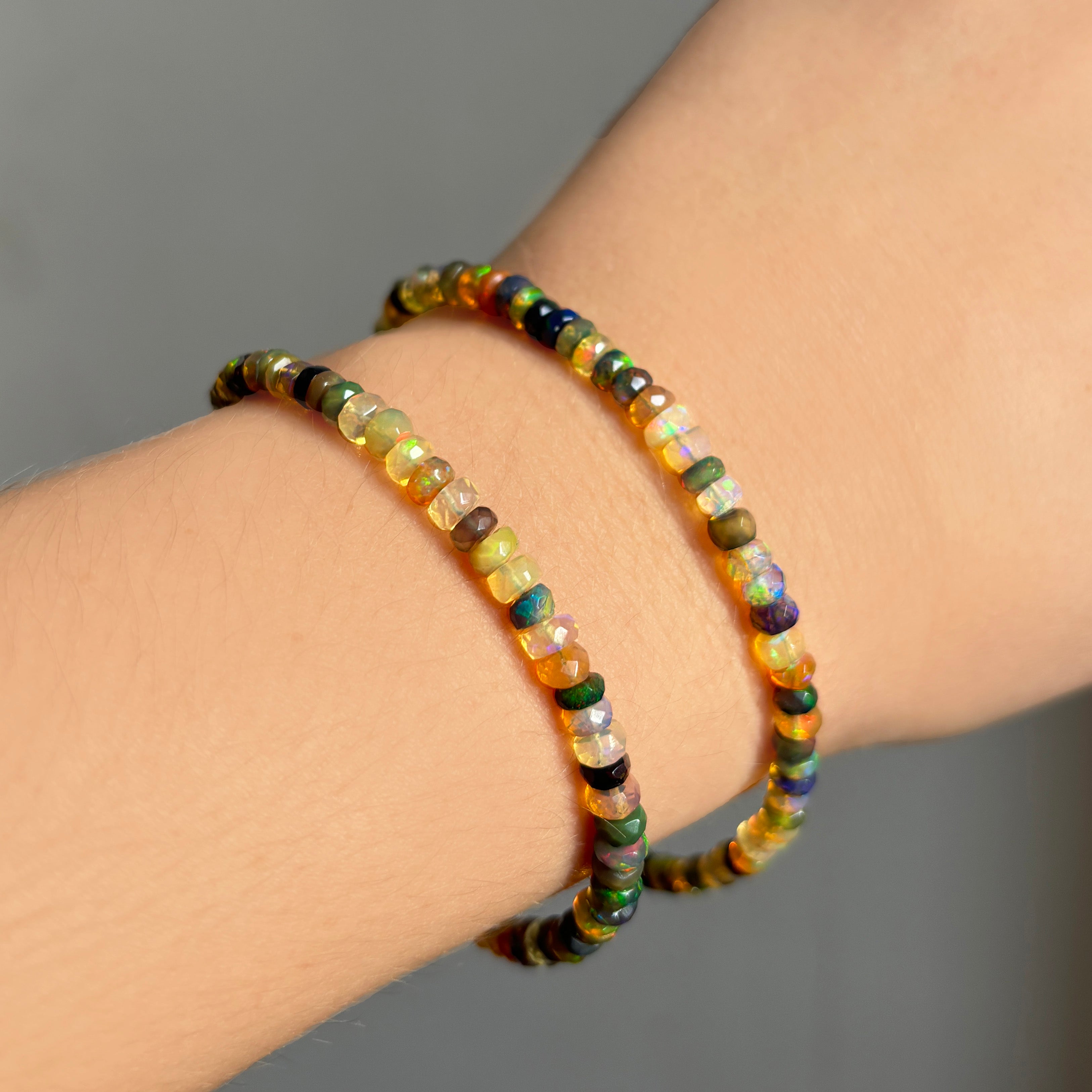 Shimmering beaded bracelet made of faceted opals in shades of green, yellow, brown, black, and clear on a gold linking lobster clasp.