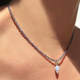 Blue lace agate acorn drop charm. Styled on a neck hanging from a beaded slim gemstone necklace.
