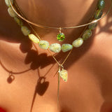 Prehnite acorn drop charm. Styled on a neck hanging from a beaded necklace with the A letter charm, quill spike charm, and round solitaire charm.