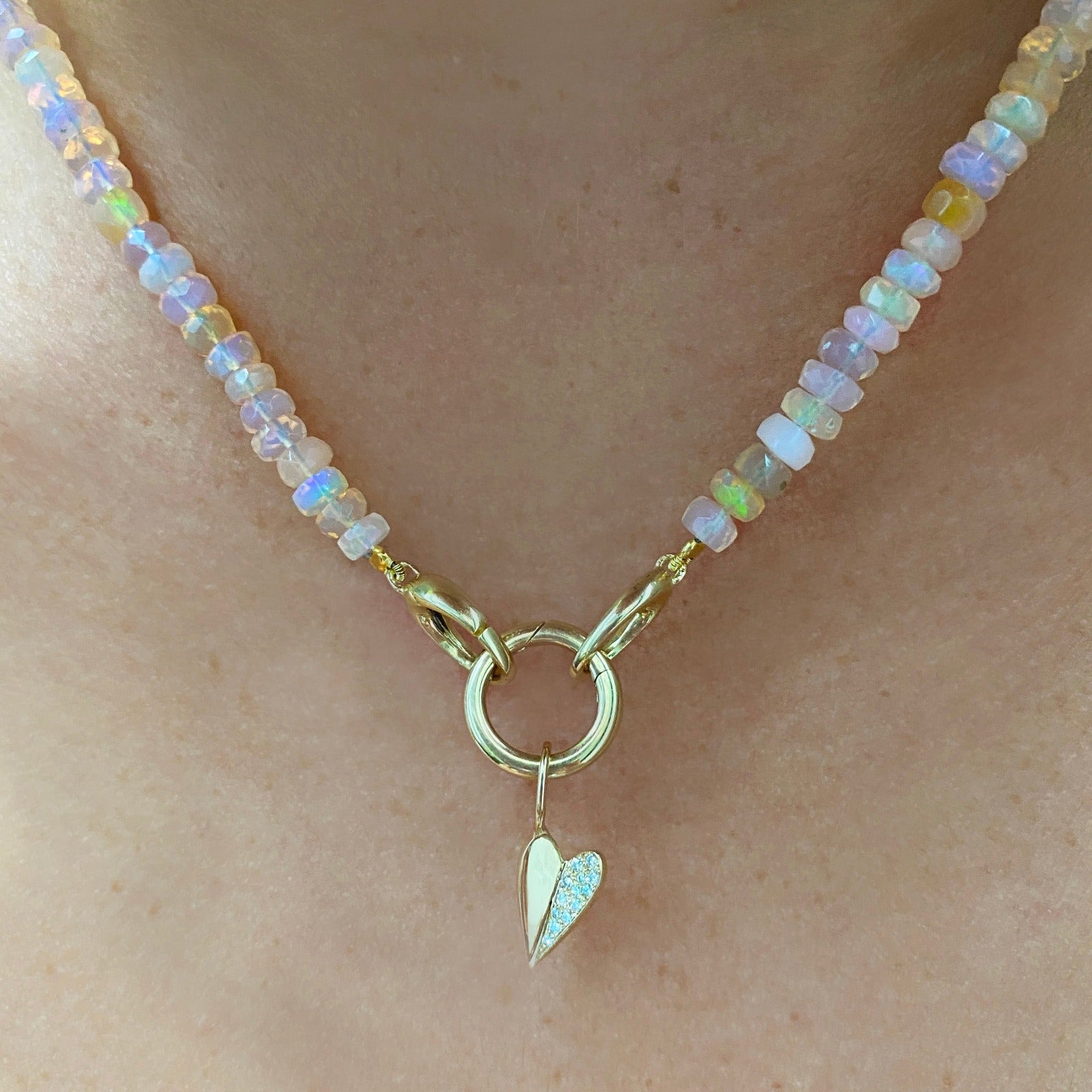 14k recycled gold 13mm Plain Round Charm Lock. Styled on a neck with a folded paved heart charm hanging from oval clasps of a beaded necklace.