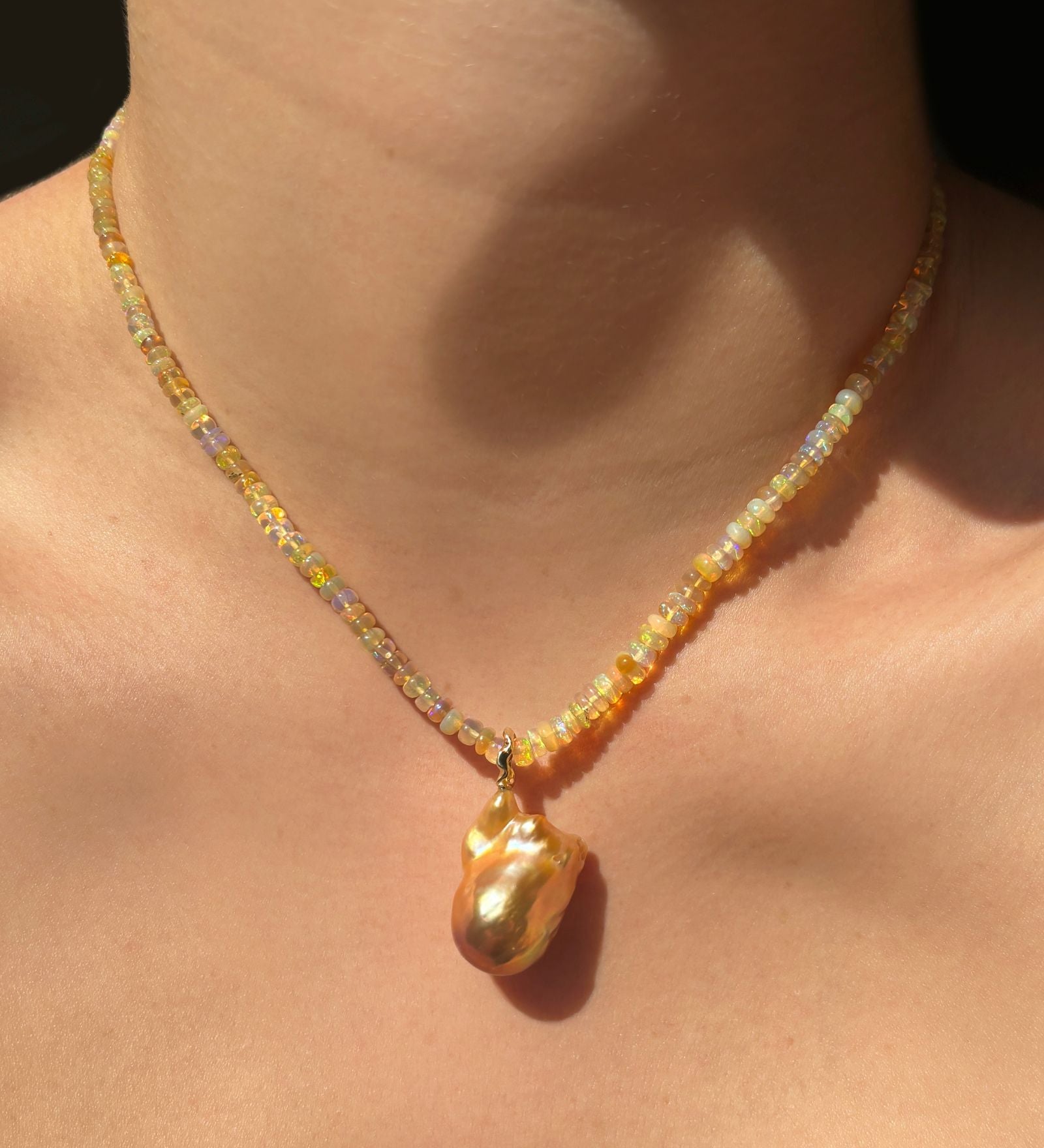 Eclipse Opal Necklace with Golden Baroque Pearl Charm hanging from Neck.