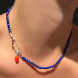 AMANDA PEARL Faceted Lapis Necklace on Recycled Sterling Silver Evolution Clasp with paperclip charm lock with carnelian cabochon, holding a carnelian drop charm on a model's neck.