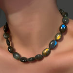 Gemmy and flashy labradorite oval beads on a model's neck.