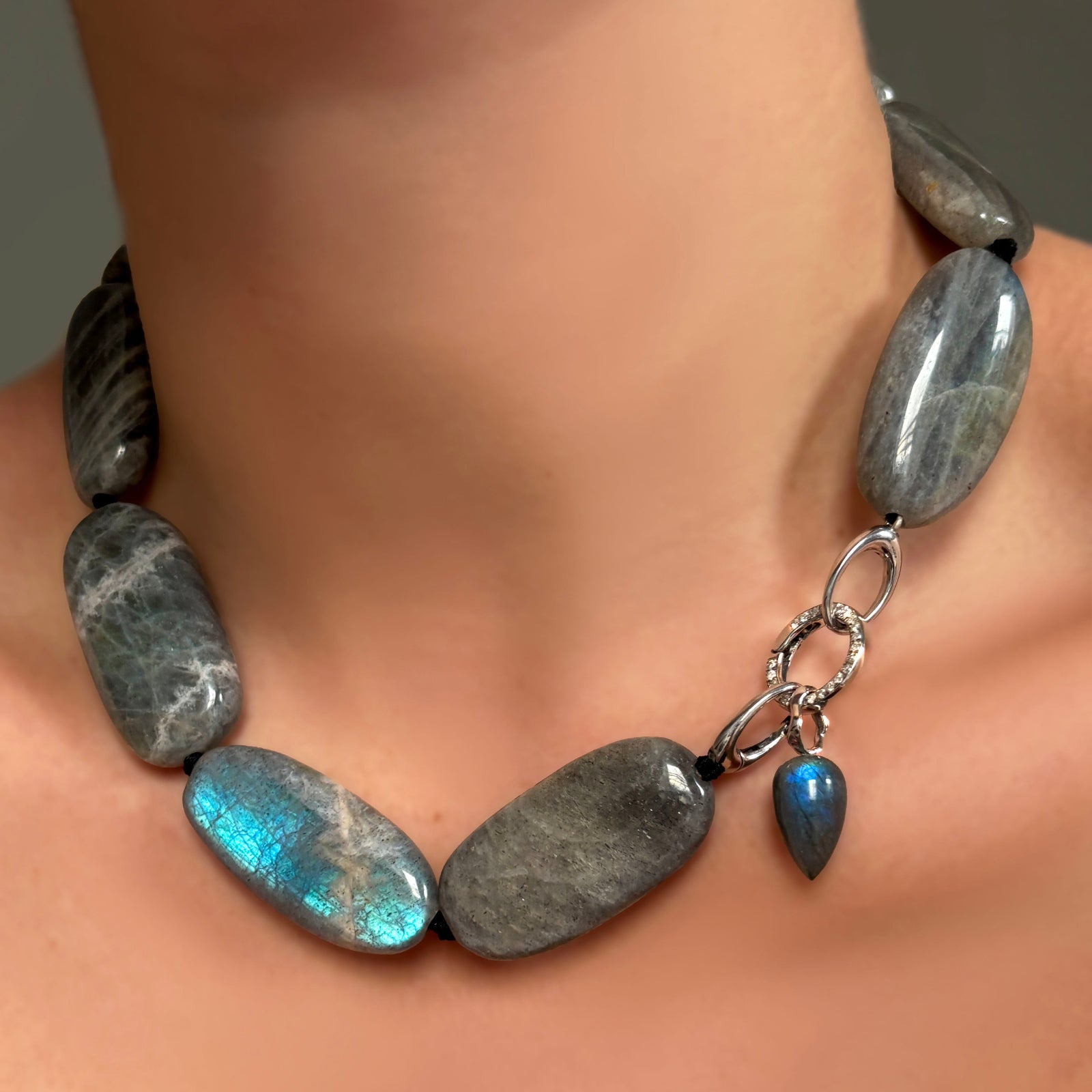 Labradorite Long Oval Necklace with Round pavé face charm lock and Labradorite drop charm on 14K recycled white gold ripple bale on a model's neck. 