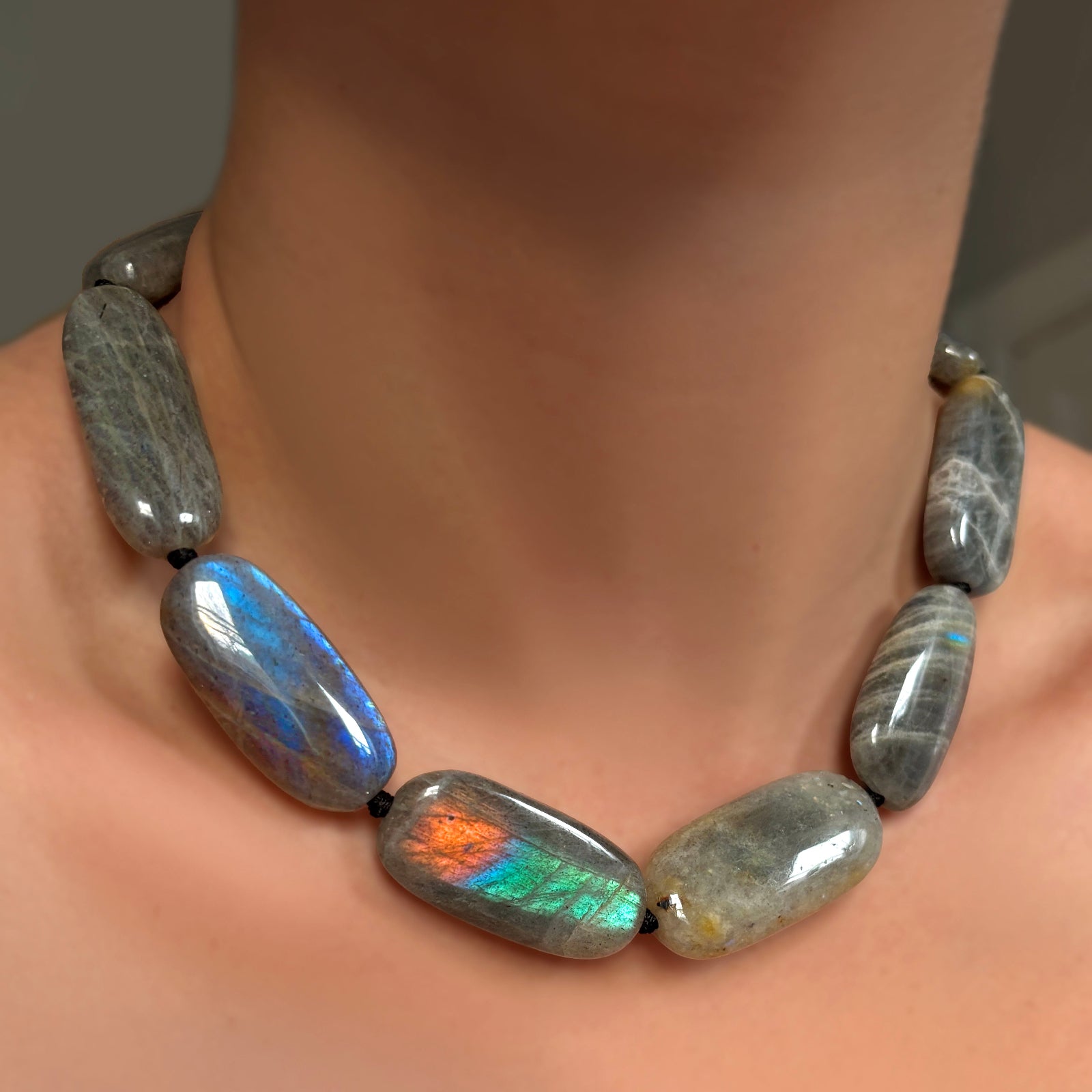 Labradorite Long Oval Necklace with black knotted thread on a model's neck.