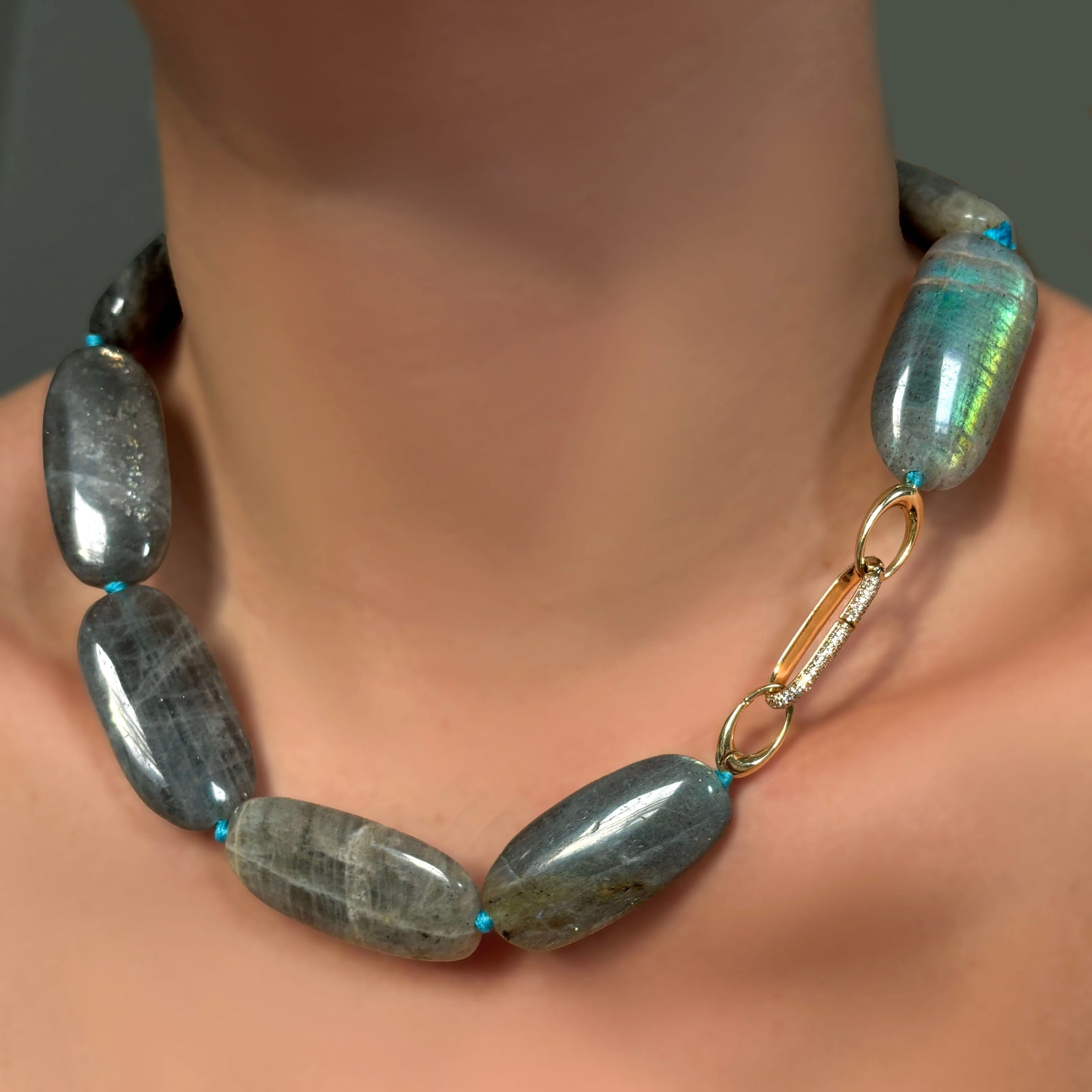 Labradorite Long Oval Necklace with blue knotted thread, with pavé oval charm lock on a model's neck, with 14K recycled yellow gold evolution clasp. 