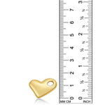 A 14K recycled yellow gold molten heart charm from AMANDA PEARL sits against a ruler for scale.