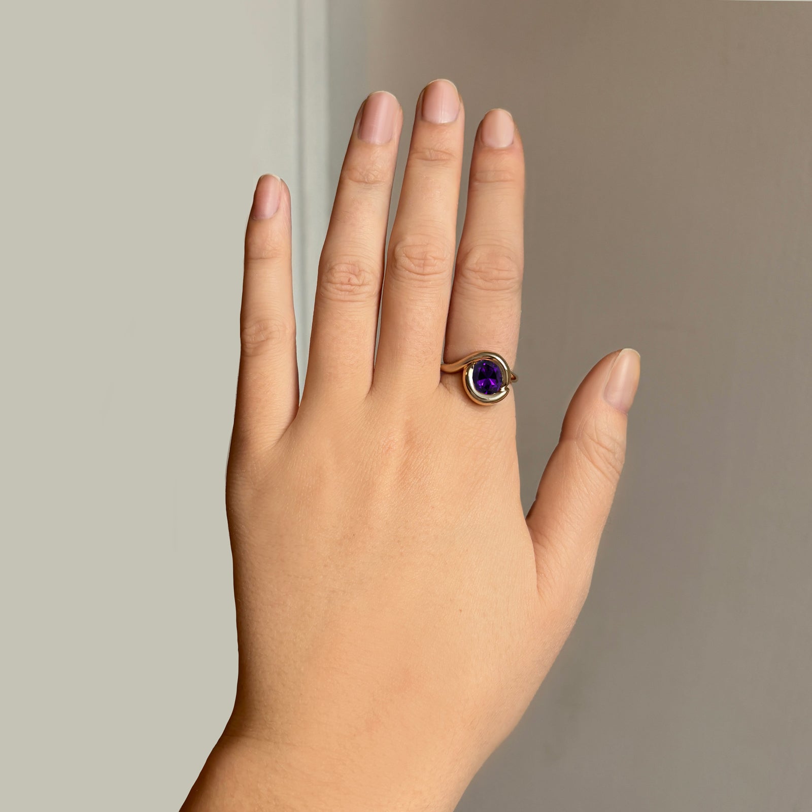 Molten knot ring with deep, rich purple amethyst gemstone on a model's hand.