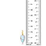 A rainbow moonstone drop charm with a 14K yellow gold ripple bale stands against a ruler for scale. 