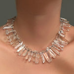 A Rock crystal collar, strung on black thread with knots, on a model's neck.