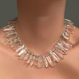 A Rock crystal collar, strung on black thread with knots, on a model's neck.