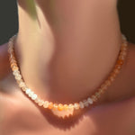Ombré peachy strawberry quartz rondelle necklace on a model's neck.