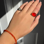 A model wearing an AMANDA PEARL faceted carnelian beaded bracelet along with a recycled sterling silver molten skull pinky ring and pebble ring with carnelian cabochon.