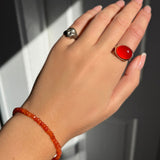 A model wearing an AMANDA PEARL faceted carnelian beaded bracelet along with a recycled sterling silver molten skull pinky ring and pebble ring with carnelian cabochon.