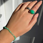 Model wearing an AMANDA PEARL recycled sterling silver molten ring, pebble ring with chrysoprase cabochon, and faceted chrysoprase beaded bracelet.