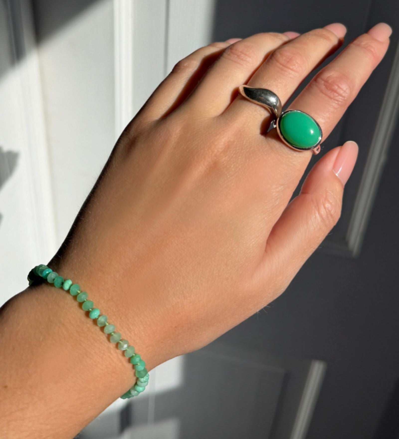 Model wearing an AMANDA PEARL recycled sterling silver molten ring, pebble ring with chrysoprase cabochon, and faceted chrysoprase beaded bracelet.