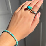 A model wearing an AMANDA PEARL turquoise rondelle bracelet, recycled sterling silver pebble ring with turquoise cabochon, and molten ring.