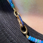 14K gold Small Sapphire Charm Lock styled on a neck locked onto oval clasps of a faceted beaded opal necklace.