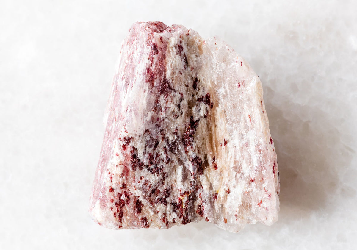A white and red quartz crystal sits on a white background.