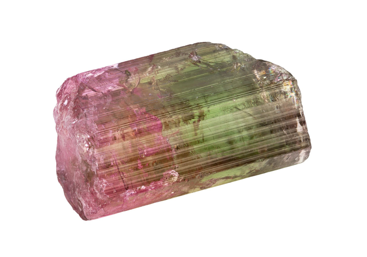 A raw tourmaline gemstone sits on a white background.