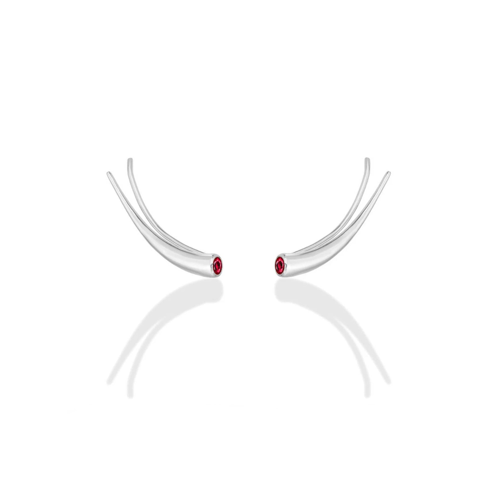 A pair of 14k recycled white gold curved climber earrings with a quill spike shape and a bezel set round ruby on a white background.