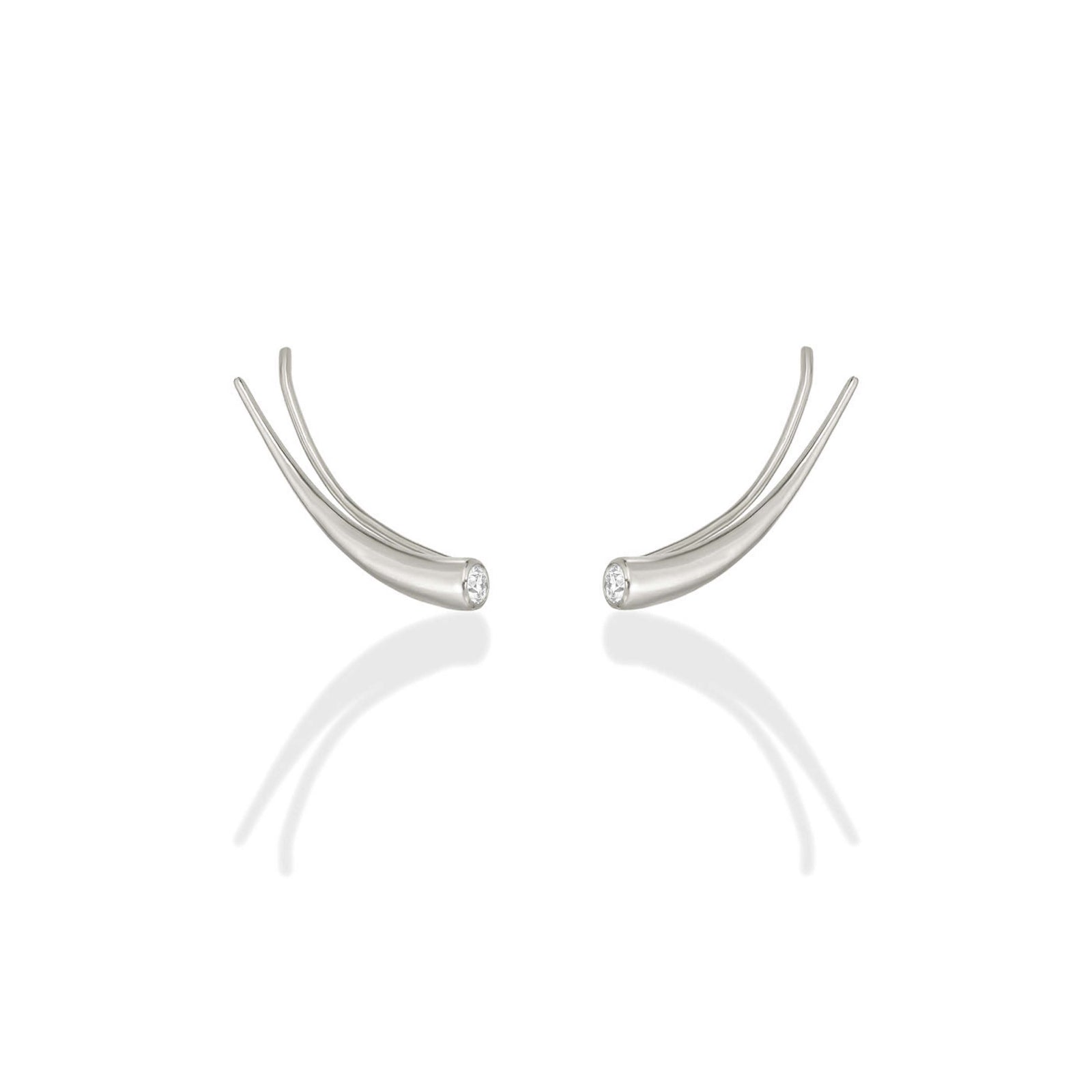 A pair of 14k recycled white gold curved climber earrings with a quill spike shape and a bezel set round diamond on a white background.