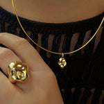 14K recycled Yellow Gold skull charm styled on the omega choker with the skull ring in the foreground on a hand