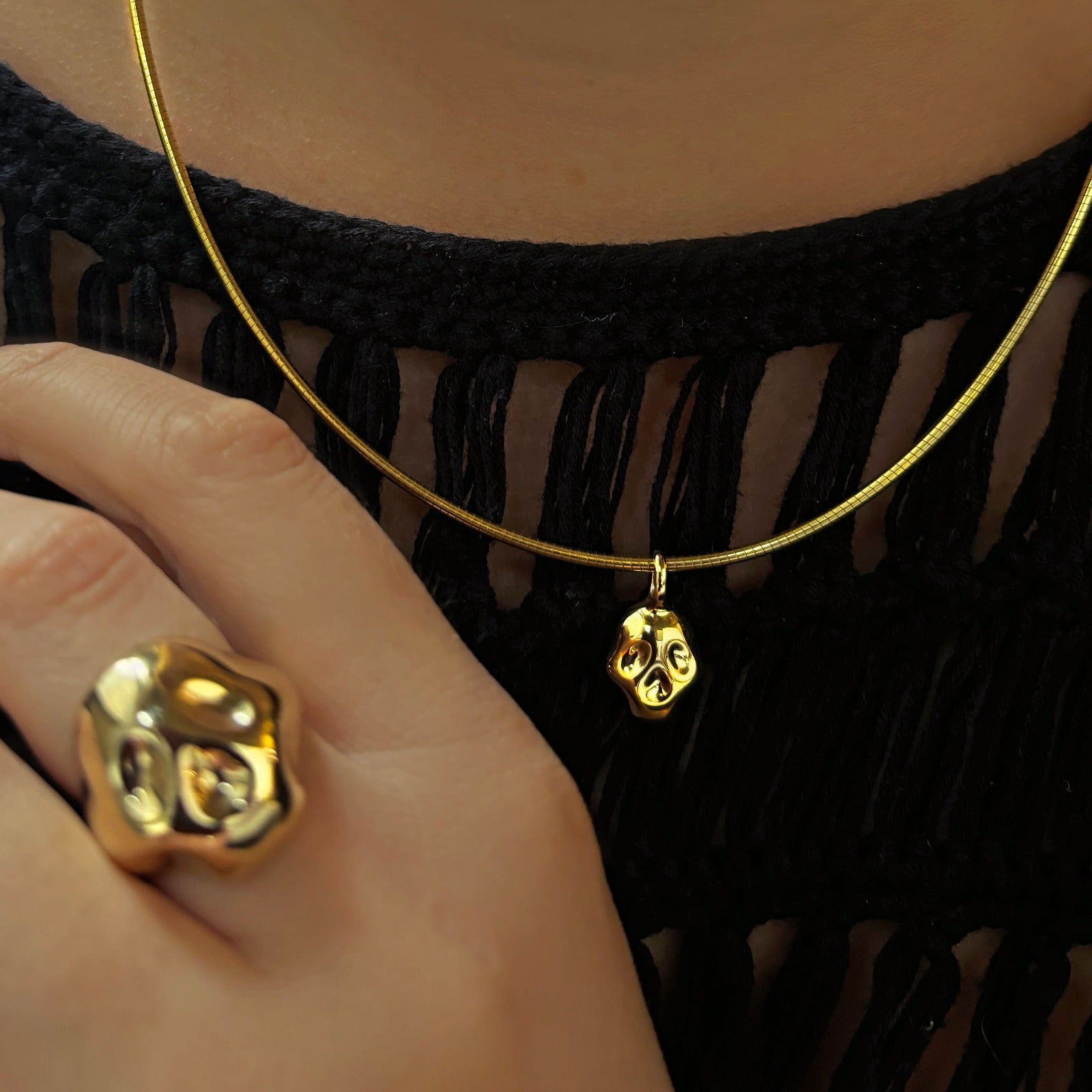 14K recycled Yellow Gold skull charm styled on the omega choker with the skull ring in the foreground on a hand