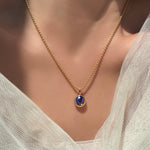 2mm bead chain in 14k yellow gold with a molten solitaire charm with round sapphire on a model's neck with some bridal tulle surrounding it.