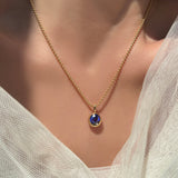2mm bead chain in 14k yellow gold with a molten solitaire charm with round sapphire on a model's neck with some bridal tulle surrounding it.