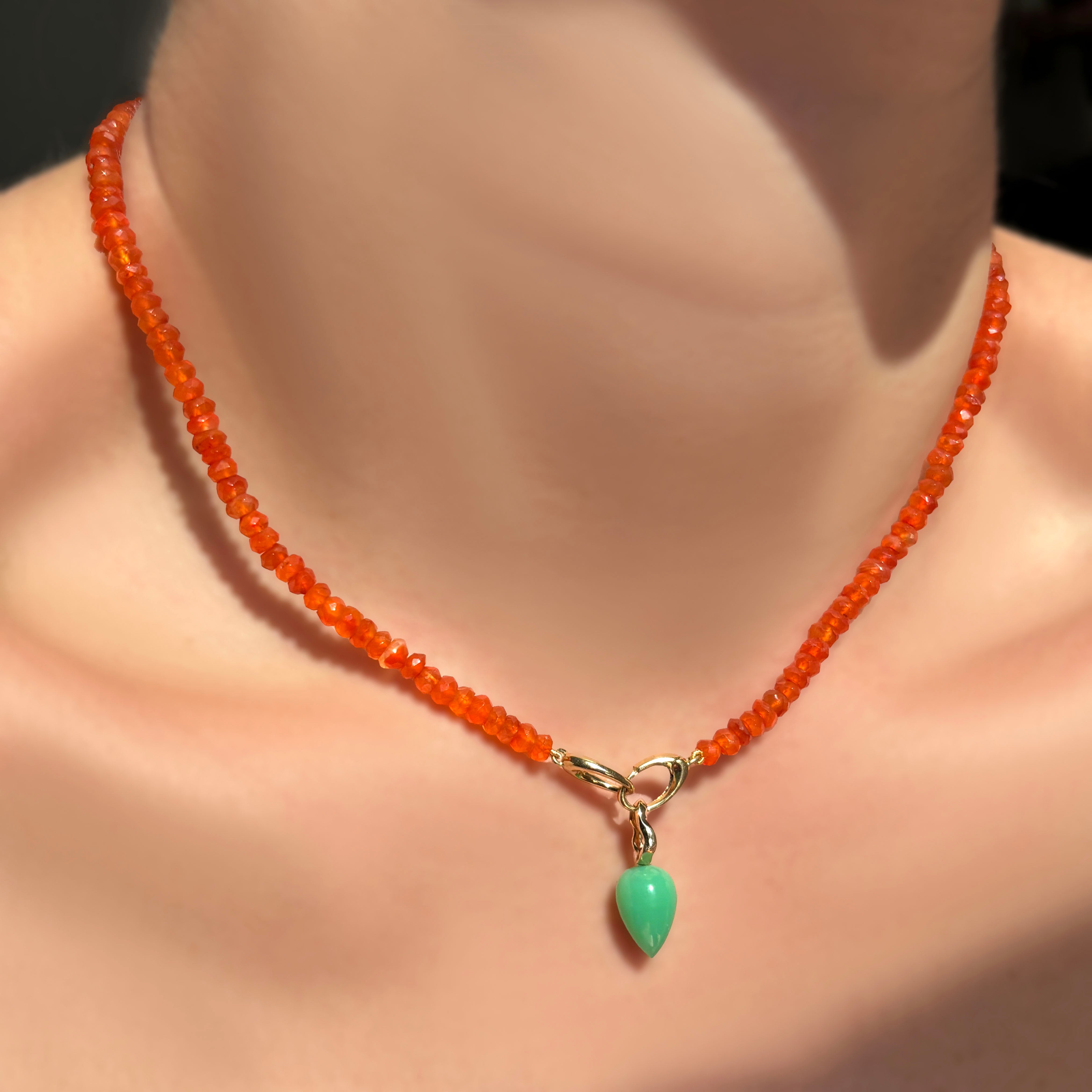 Faceted carnelian with a chrysoprase drop charm hanging in the linking ovals clasp on a model's neck.
