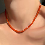 Faceted carnelian necklace on a model's neck.