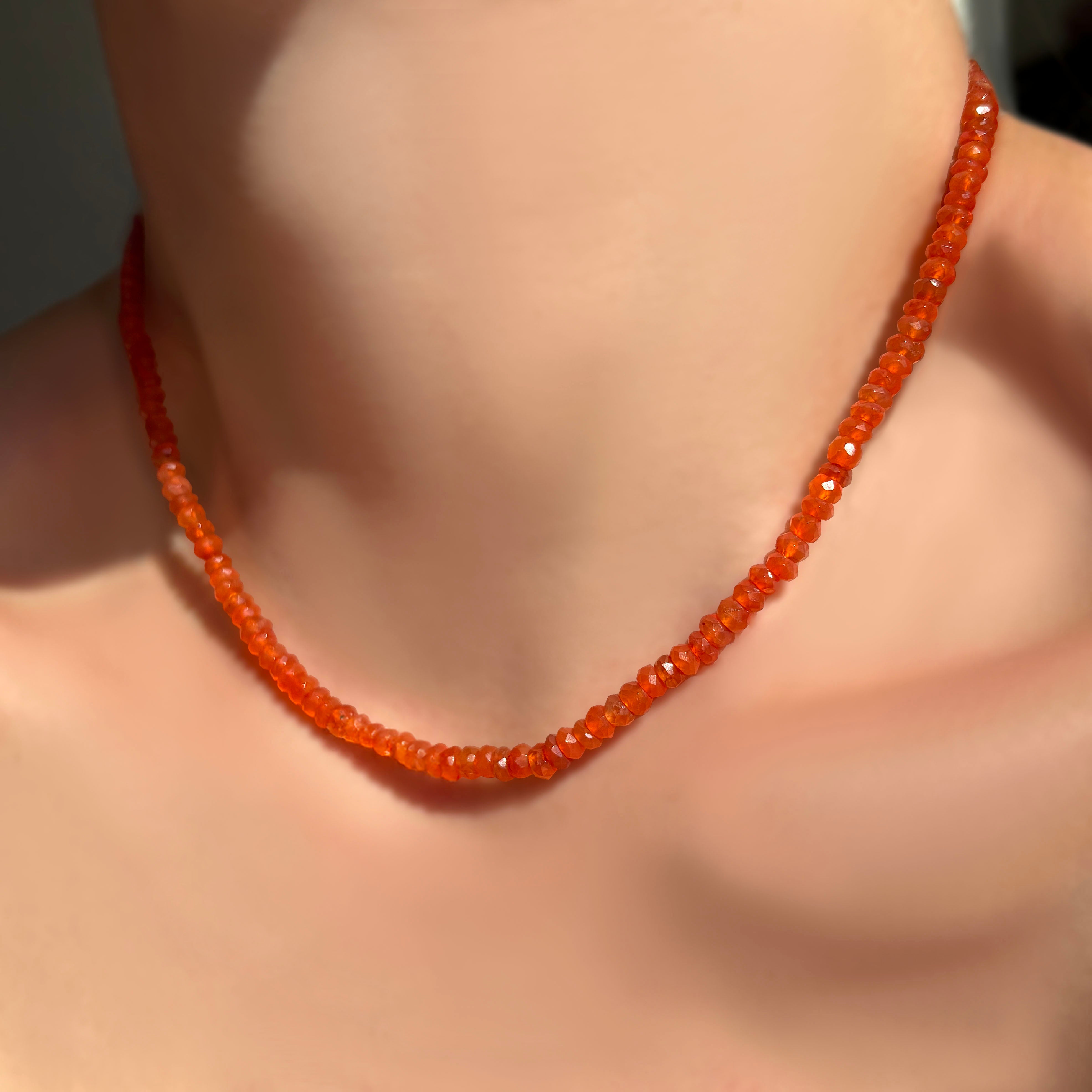 Faceted carnelian necklace on a model's neck.